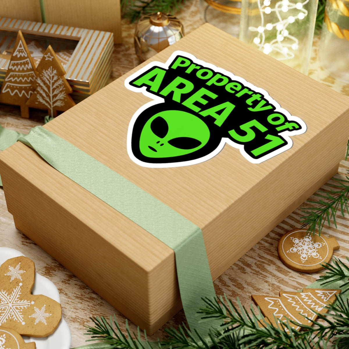 Wooden gift box with 'Property of Area 51' alien sticker on a festive background with cookies and decorations.